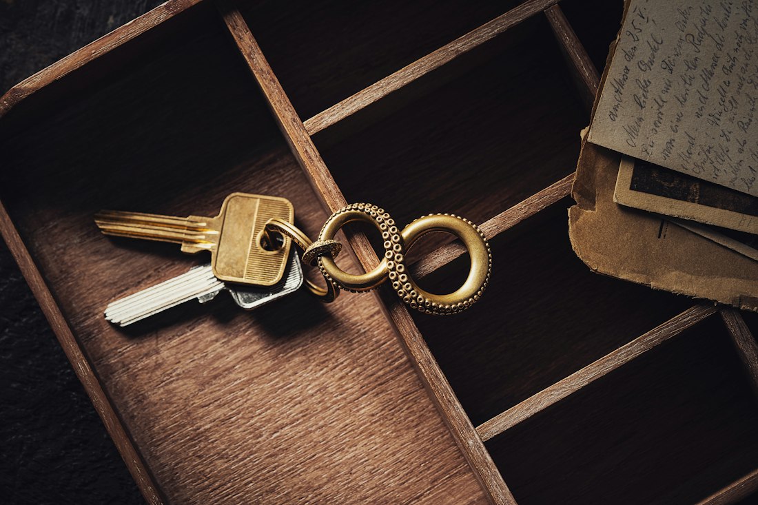 House keys resting in a wooden keepsake box beside old letters